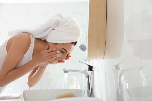 woman washing her face over a sink