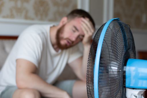 man relying on a fan to keep him cool