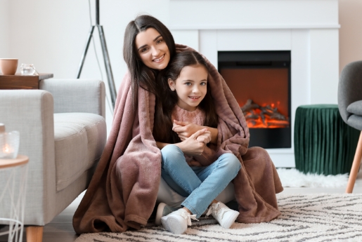 Mother and Daughter in living room with a blanket on waiting on furnace repair.